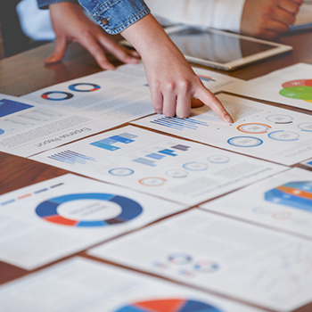 Photo of person pointing at charts on a table.